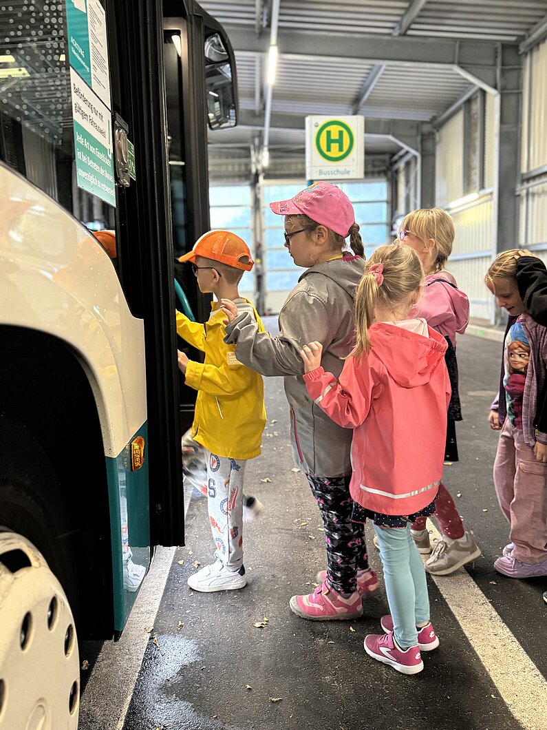 Mädchen und Jungen steigen in einen Linienbus ein.