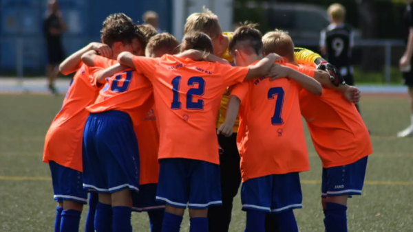 Kinder-Fußballer bilden sich umarmend einen Kreis