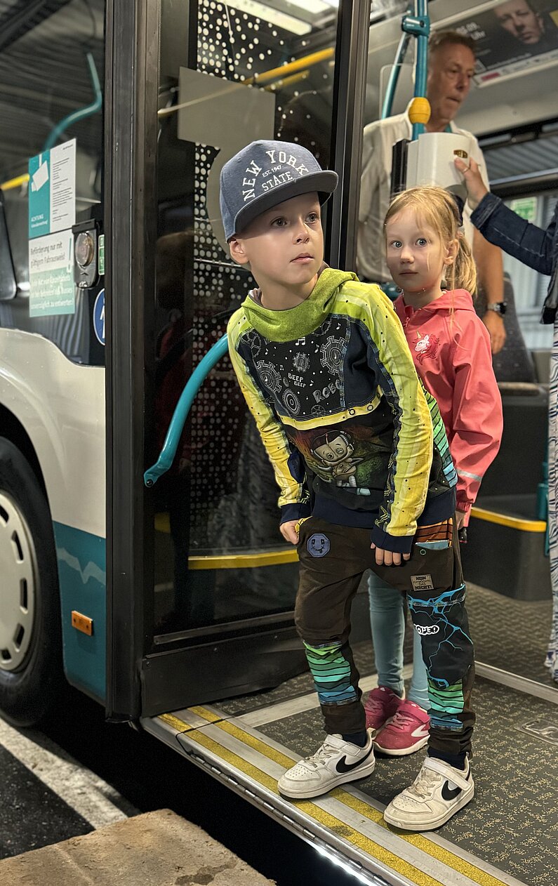 Ein Junge steht in der geöffneten Bustür und nach links, bevor er aussteigt. 