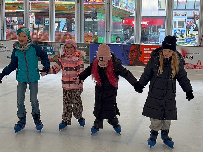 Vier Mädchen Hand in Hand auf dem Eis. 