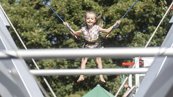 Mädchen an Sicherungsseilen auf einem Trampolin.