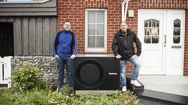 Zwei Männer stehen an einer Wärmepumpe.