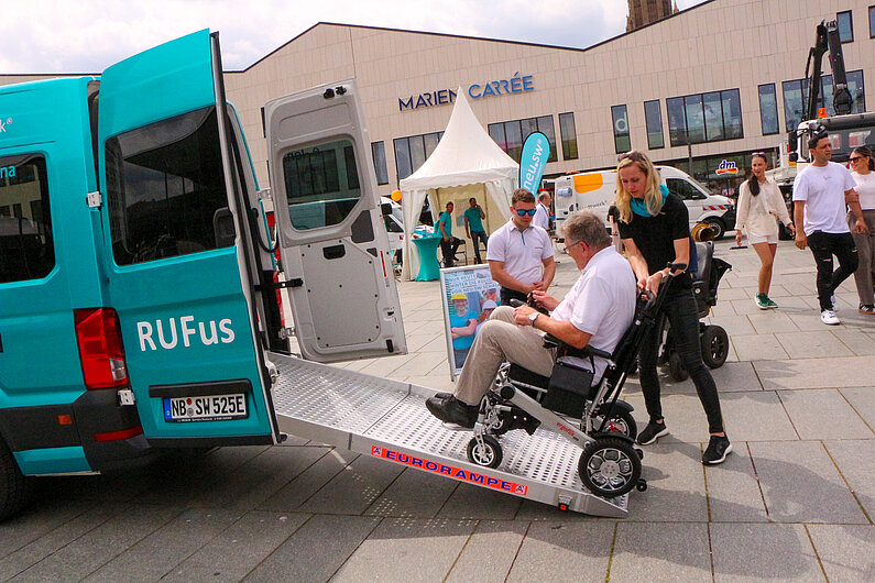 Ein Rollstuhlfahrer fährt auf einer Rampe in einen Kleinbus.