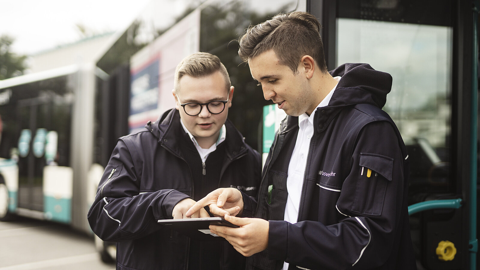 Zwei Busfahrer schauen sich Informaionen auf dem Tablet