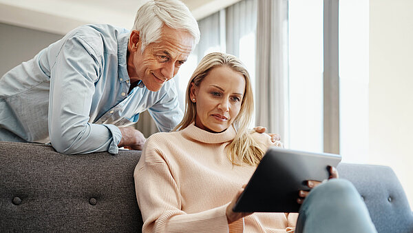 Älteres Paar schaut auf Tablet.