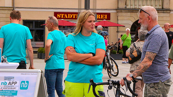 Mitarbeiterin von neu.sw auf dem Neubrandenburger Markt im Gespräch mit einem Kunden