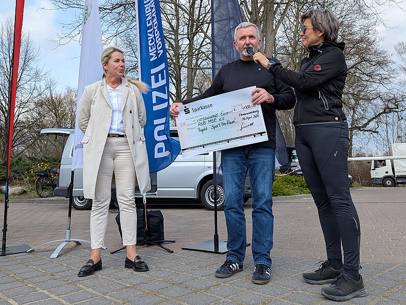 SAbine Schmidt von der Sparkasse (links) und Polizeidirektorin Antje Finnern (rechts) übergeben den Spendenscheck an ASB-Geschäftsführer Frank Brehe.
