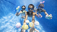 Kinder tauchen im Schwimmbad mit Ostereiern.