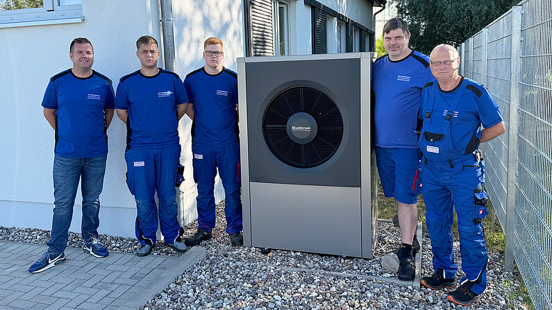 Fünf Mitarbeiter von nb-haustechnik im Blaumann an einer Wärmepumpe.