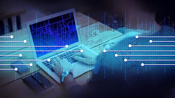 Hände auf Tastatur eines Laptops. Darüber digitale Weltkarte, Datenströme und Binärcodes.