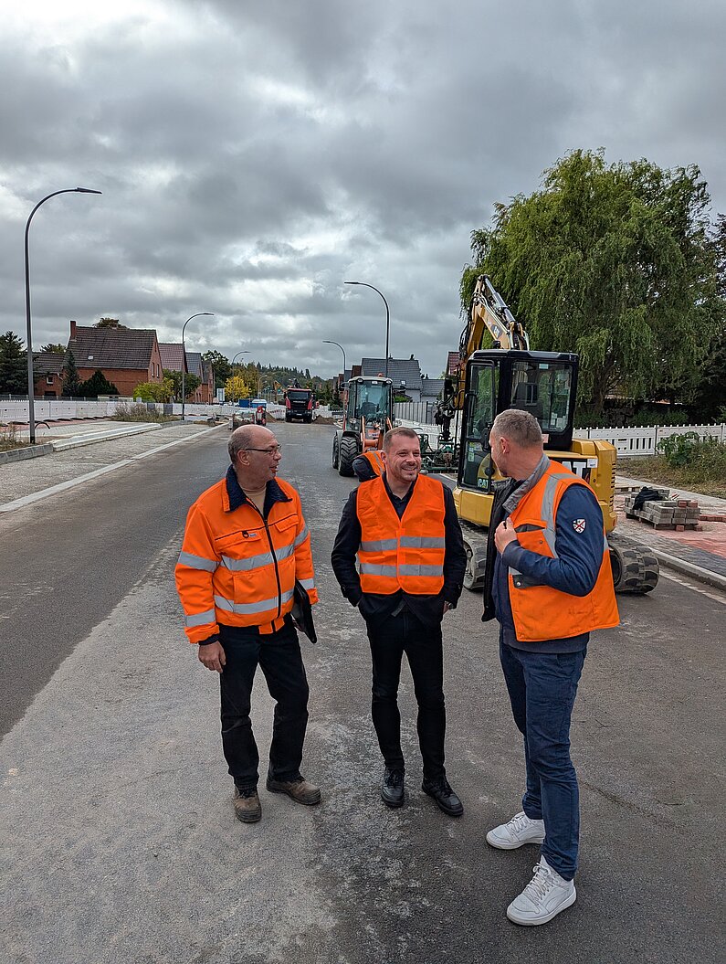 Zwei Projektverantwortliche auf der Baustelle im Gespräch mit Oberbürgermeister Niko Klose. 