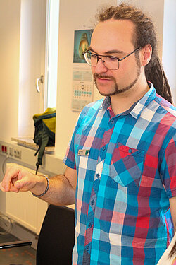 Mann mit Brille und Dreadlocks beim Erklären.