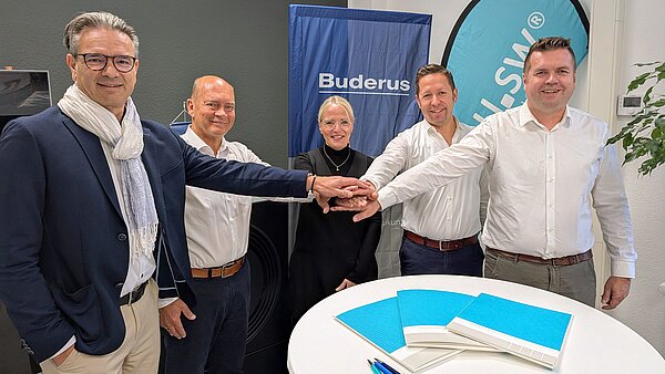 Vertreter aller beteiligte Partner legen die Hände als STartzeichen für die Kooperation zusammen.