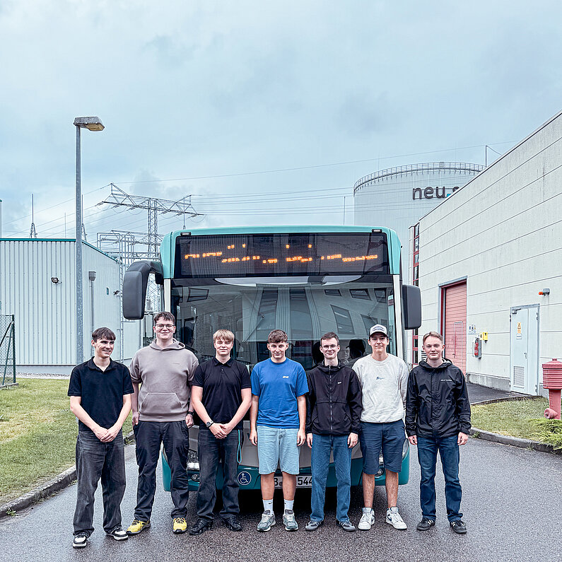 Sieben junge Männer vor einem NVB-Bus und dem neu.sw Wärmespeicher