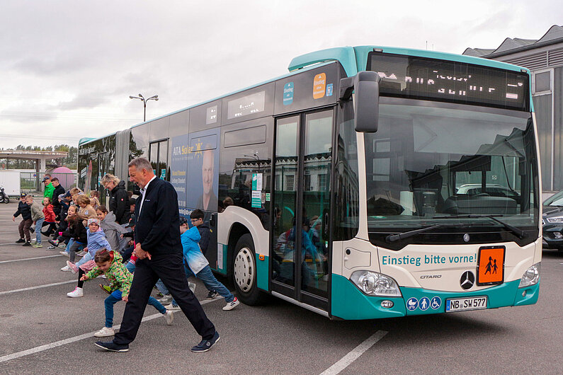 Schulklasse misst mit Schritten Abstand vom Bus.