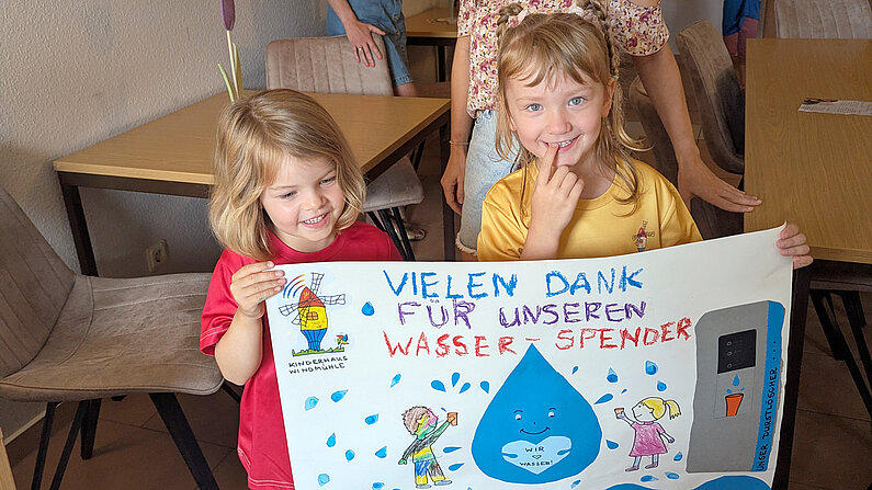 Zwei kleine Mädchen halten Danke-Plakat.