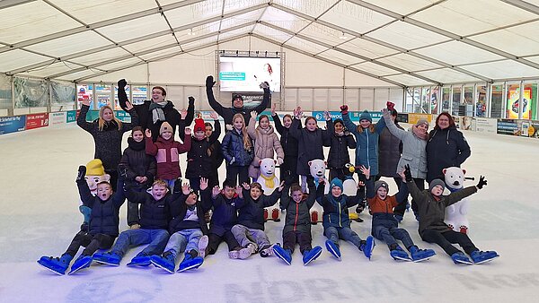 Grundschulklasse im Gruppenfoto auf der Eisfläche.