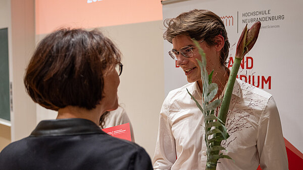 Lucas Kamrath hält eine Amaryllis-Blume in der Hand und nimmt Glückwünsche entgegen.