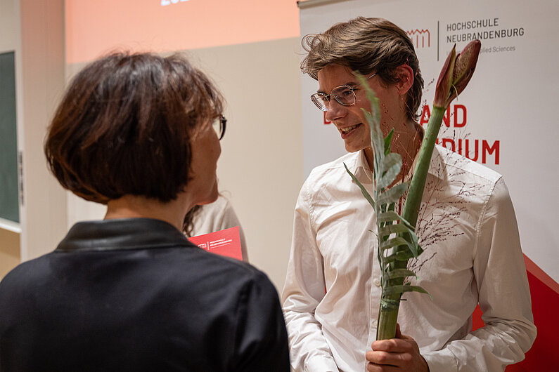 Lucas Kamrath hält eine Amaryllis-Blume in der Hand und nimmt Glückwünsche entgegen.