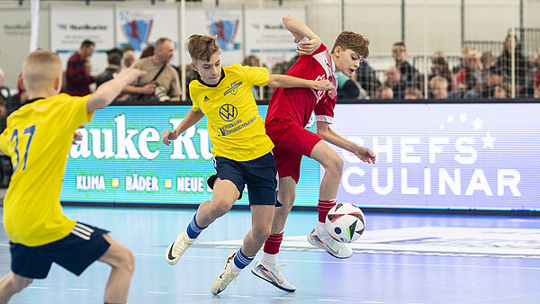 Drei Jungs im Kampf um den Ball beim Hallenturnier.
