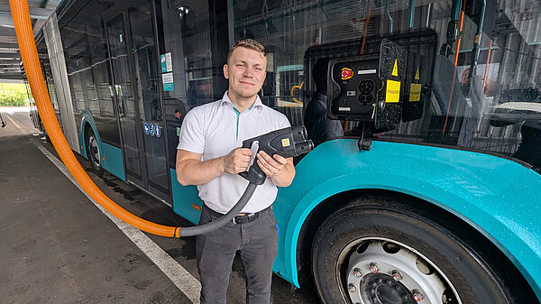 Mitarbeiter der NVB mit Stromstecker für E-Bus an einem E-Bus. 