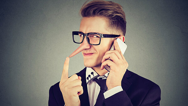 Mann mit Pinoccionase hält Hörer ans Ohr.