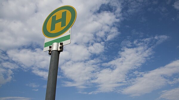 Schild Bushaltestelle vor bewölktem Himmel
