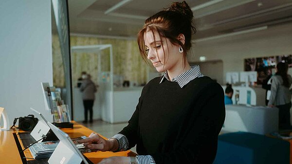Junge Frau steht an einem Tablet im Kundenbüro.