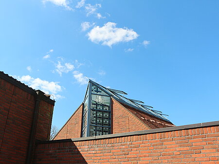 Ein Gebäude aus roten Ziegeln mit Glasdach vor blauem Himmel.