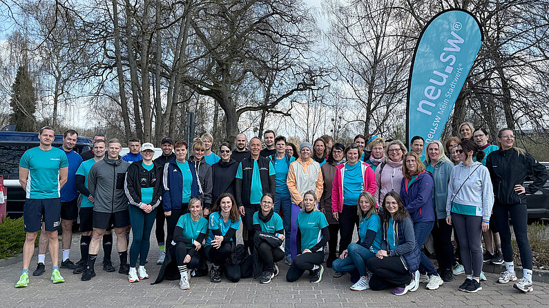 Mitarbeitende von neu.sw im Gruppenbild vor neu.sw Fahne.