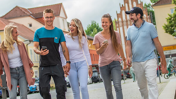 Gruppe junger Leute geht durch die Stadt mit Handy