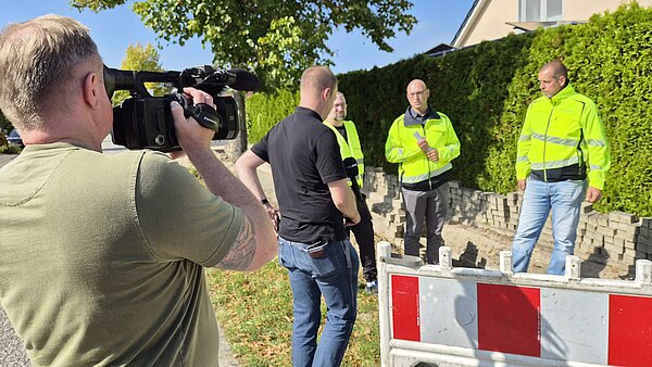 Kameramann filmt Bauleute im Reportergespräch auf Baustelle.