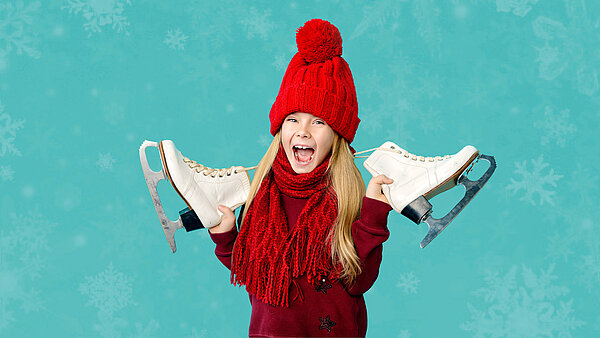 Lächelndes Mädchen in roten Wintersachen hält Schlittschuhe in den Händen.