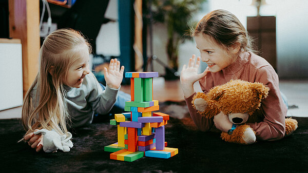 Zwei fröhliche Mädchen mit Bauklötzen.