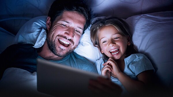 Vater und Tochter fröhlich am Tablet.