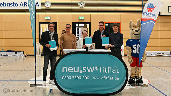 Vertreter von Verein und neu.sw bei Vertragsunterzeichnung in der Halle.