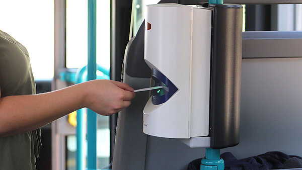 Hand mit Busfahrschein am Entwerter.