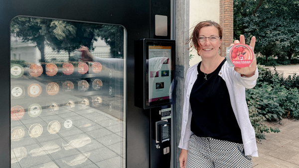 Frau steht vor Eisautomat und hält Eis in der Hand