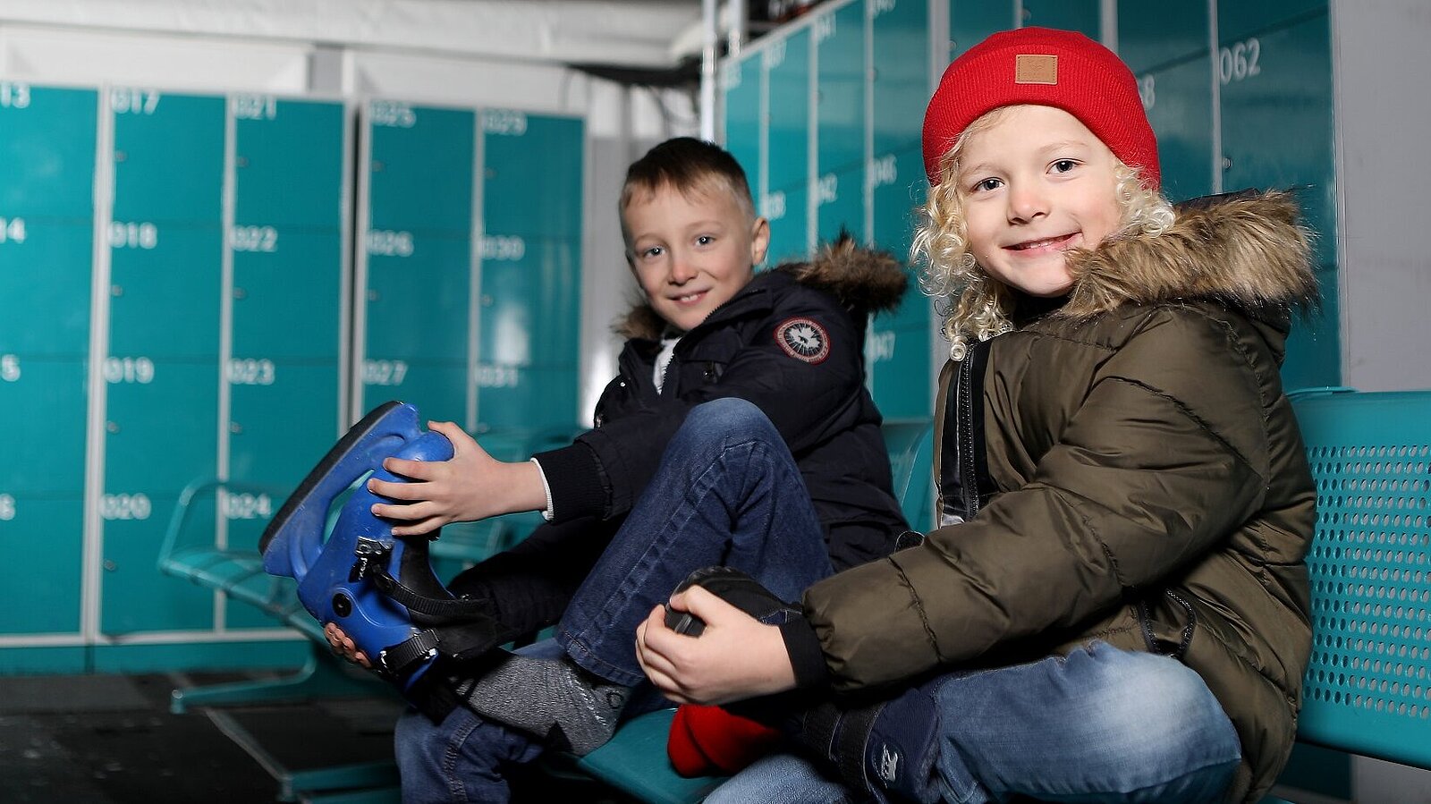 Zwei Kinder ziehen Schlittschuhe an