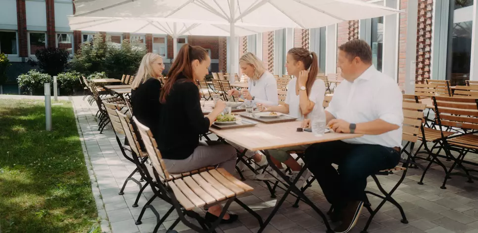 Mitarbeitergruppe draußen beim Mittagessen